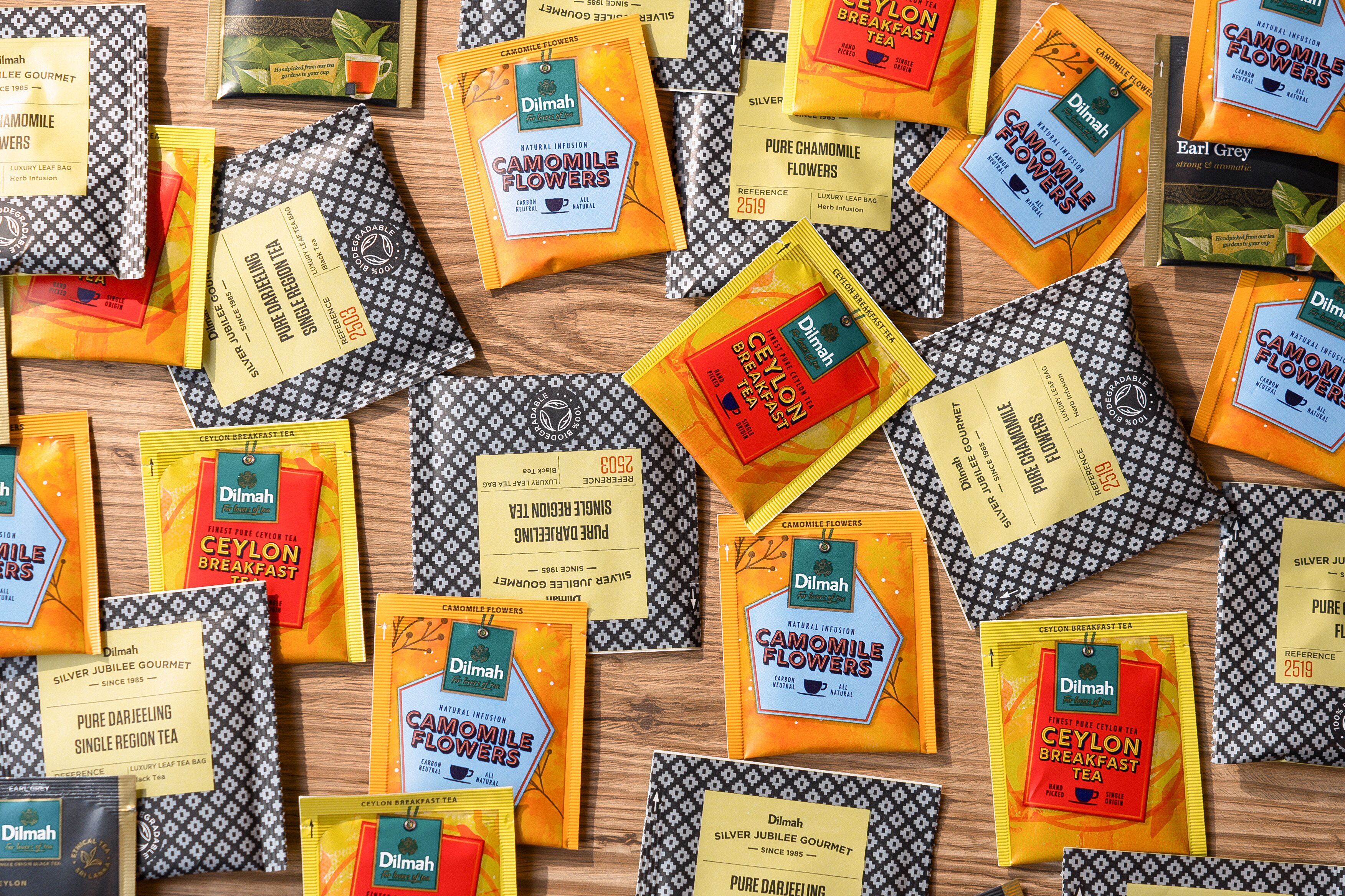 A variety of tea packages and leaf tea bags arranged on a wooden surface.