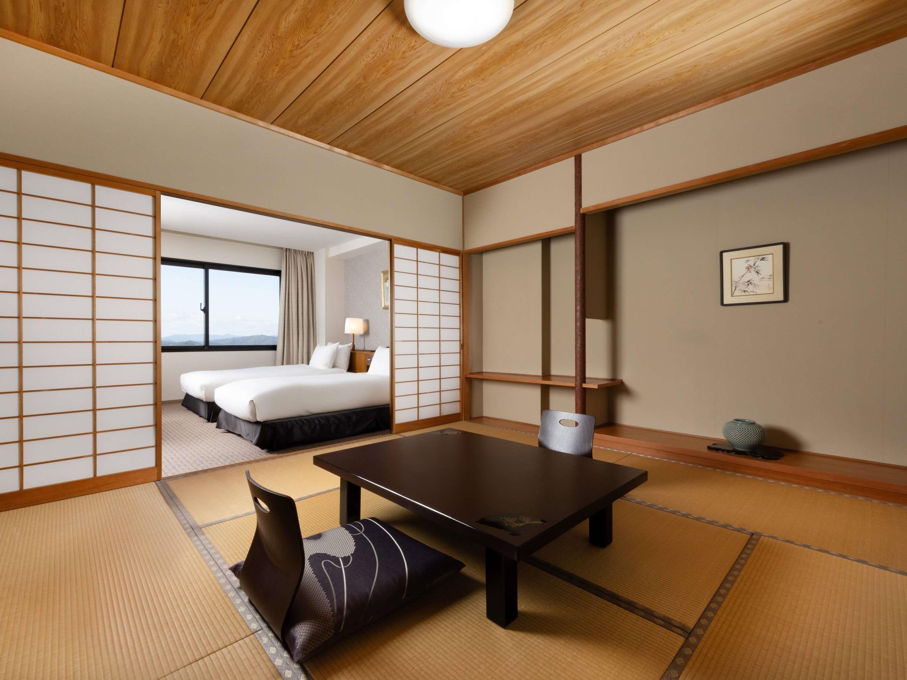 Habitació japonesa tradicional amb fons de tatami, una taula baixa i un llit amb vistes.