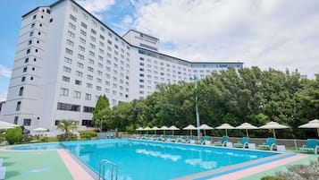 Ein Hotel mit Schwimmbad, Liegestühlen und einem großen Gebäude im Hintergrund.