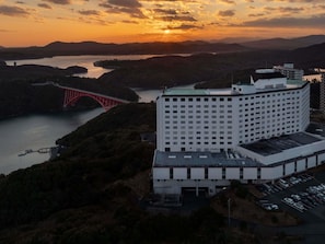 Un hotel grande con estacionamiento, un puente rojo y un río al fondo.