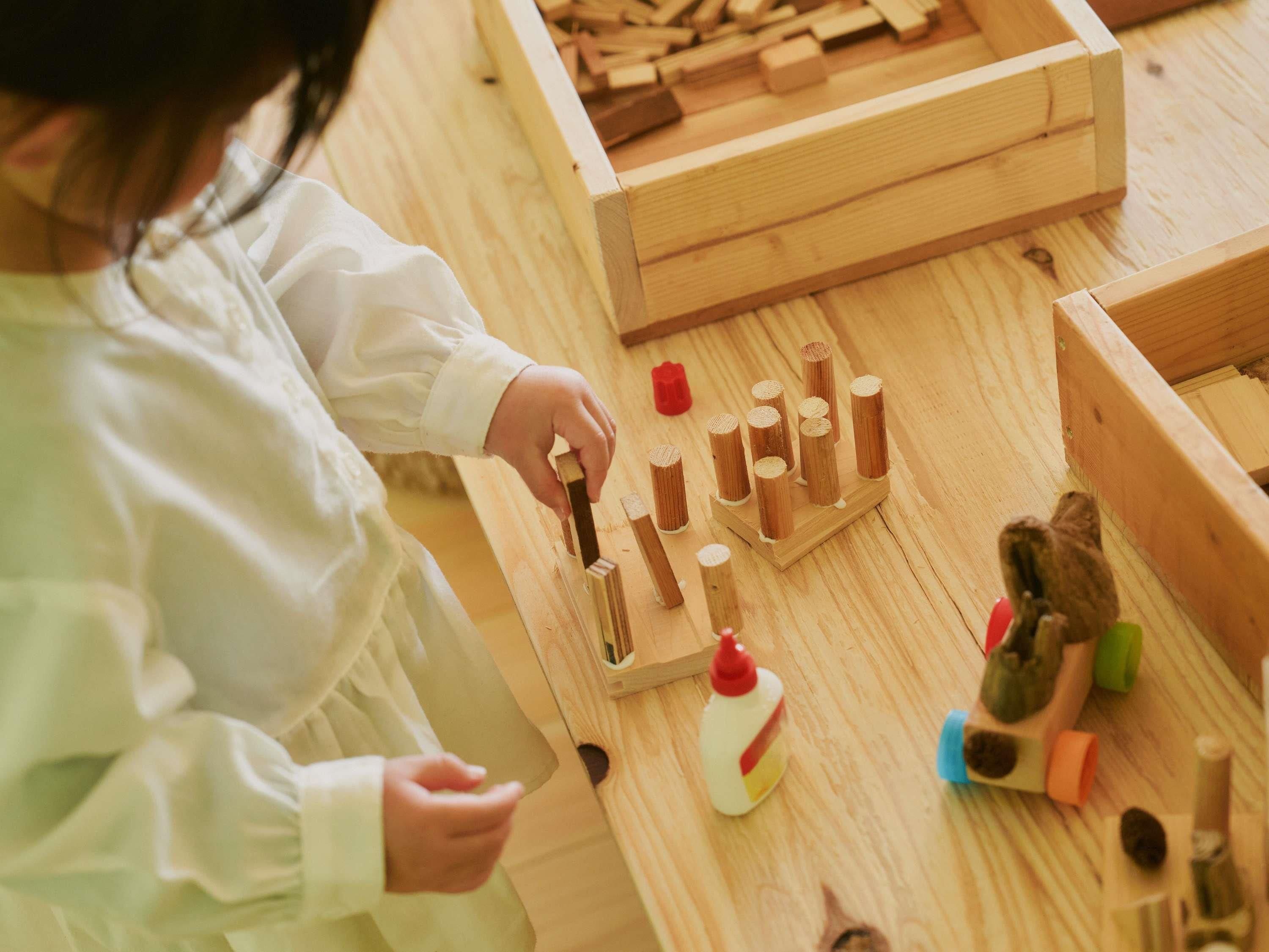 A child assembling wooden blocks on a table.