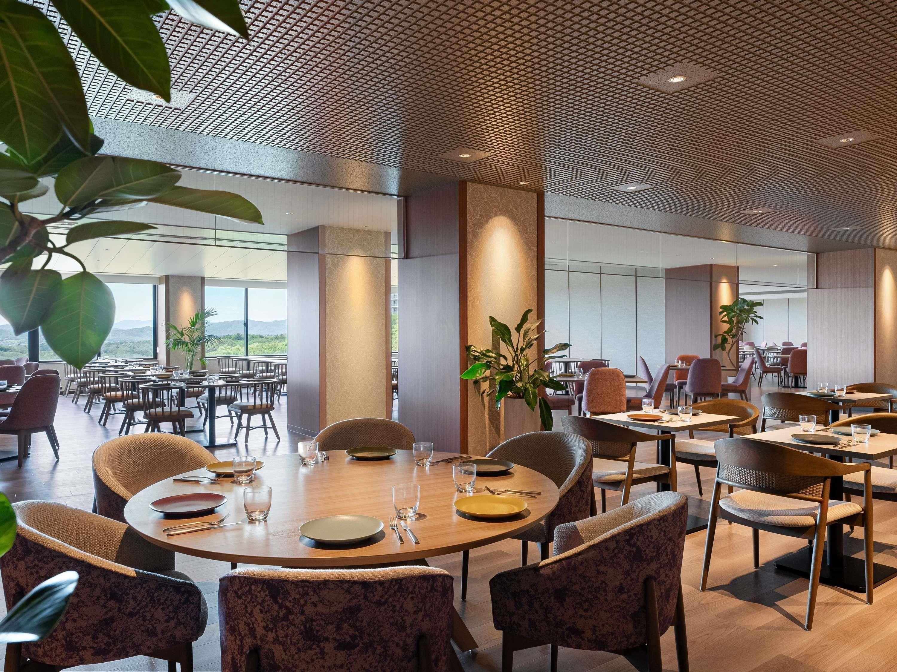 A modern dining area with round tables, chairs, and potted plants.