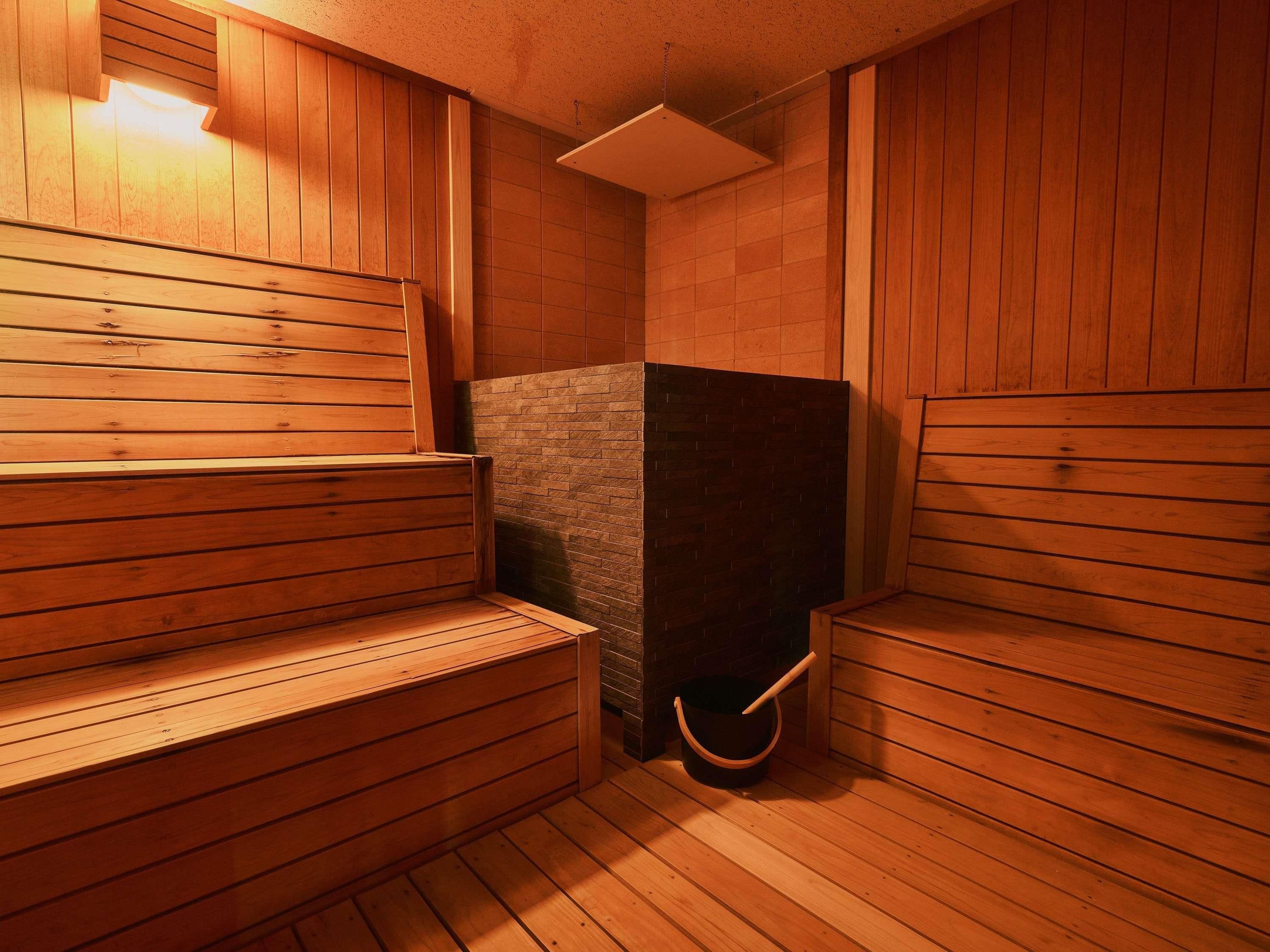 A sauna room with wooden benches and a brick wall.