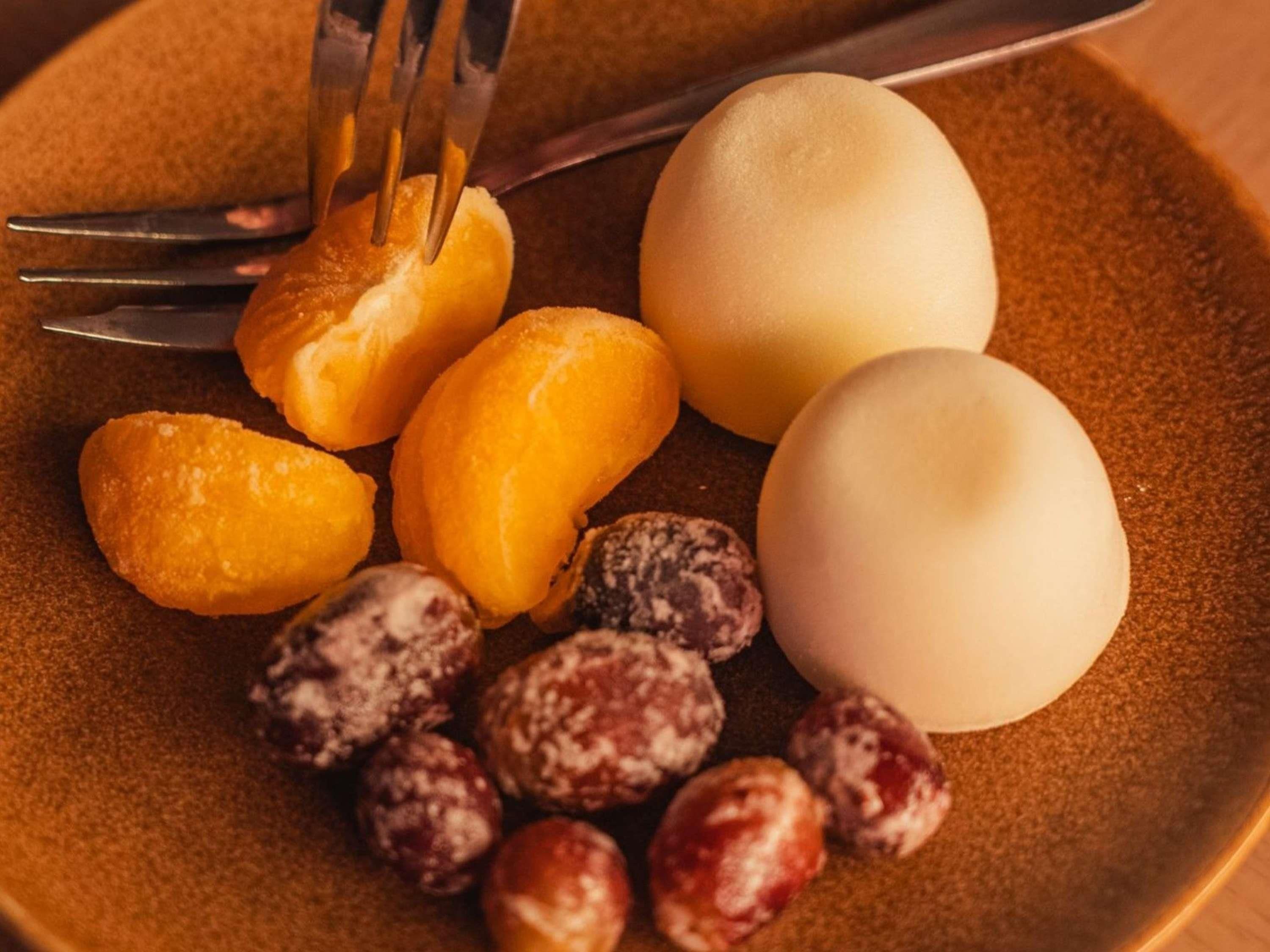 A plate with various food items including a boiled egg, orange slices, and nuts.