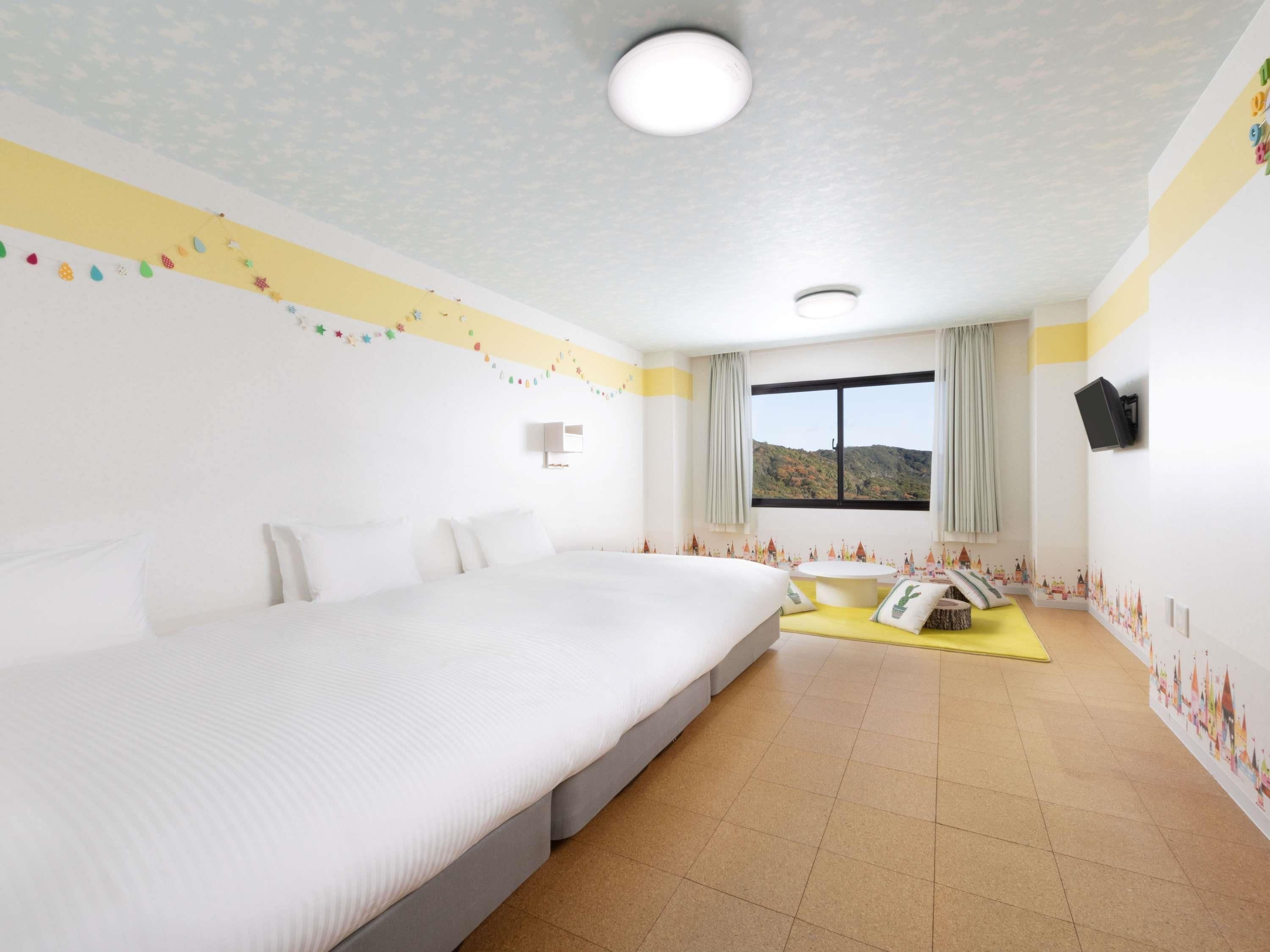 A hotel room with a large bed, a small table, and a window with a mountain view.