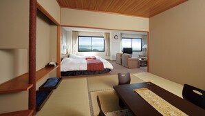 Habitación de hotel con cama, escritorio, silla, televisión y vista al exterior.