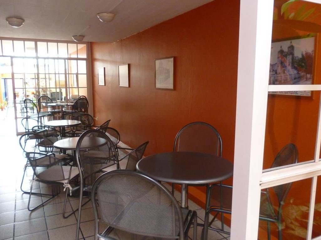 Un comedor con mesas y sillas, un ventanal grande y cuadros en la pared.