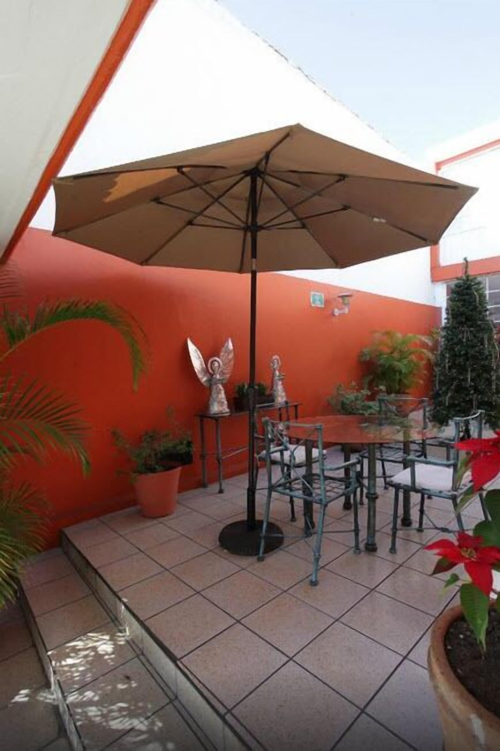 An outdoor patio with a table and chairs, a large umbrella, and potted plants.