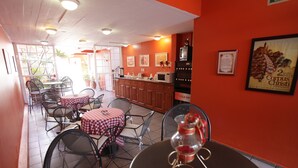 A restaurant interior with red walls, checkered tables, and metal chairs. - Hotel Camba (Oaxaca)