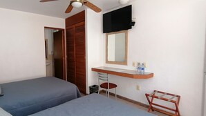 A bedroom with two beds, a wooden wardrobe, a TV mounted on the wall, a desk with a mirror, and a chair. - Hotel Camba (Oaxaca)