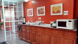A kitchen with wooden cabinets, a microwave, and framed pictures on the wall. - Hotel Camba (Oaxaca)