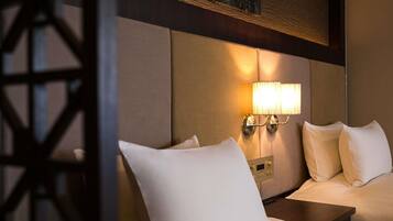 Une chambre d’hôtel avec un lit, une table de chevet et une lampe fixée au mur.