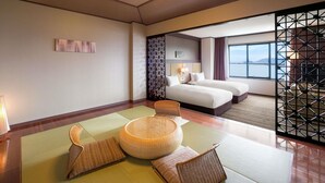 Een hotelkamer met twee bedden, een groot raam met uitzicht, tatami matten en een traditioneel Japans scherm.