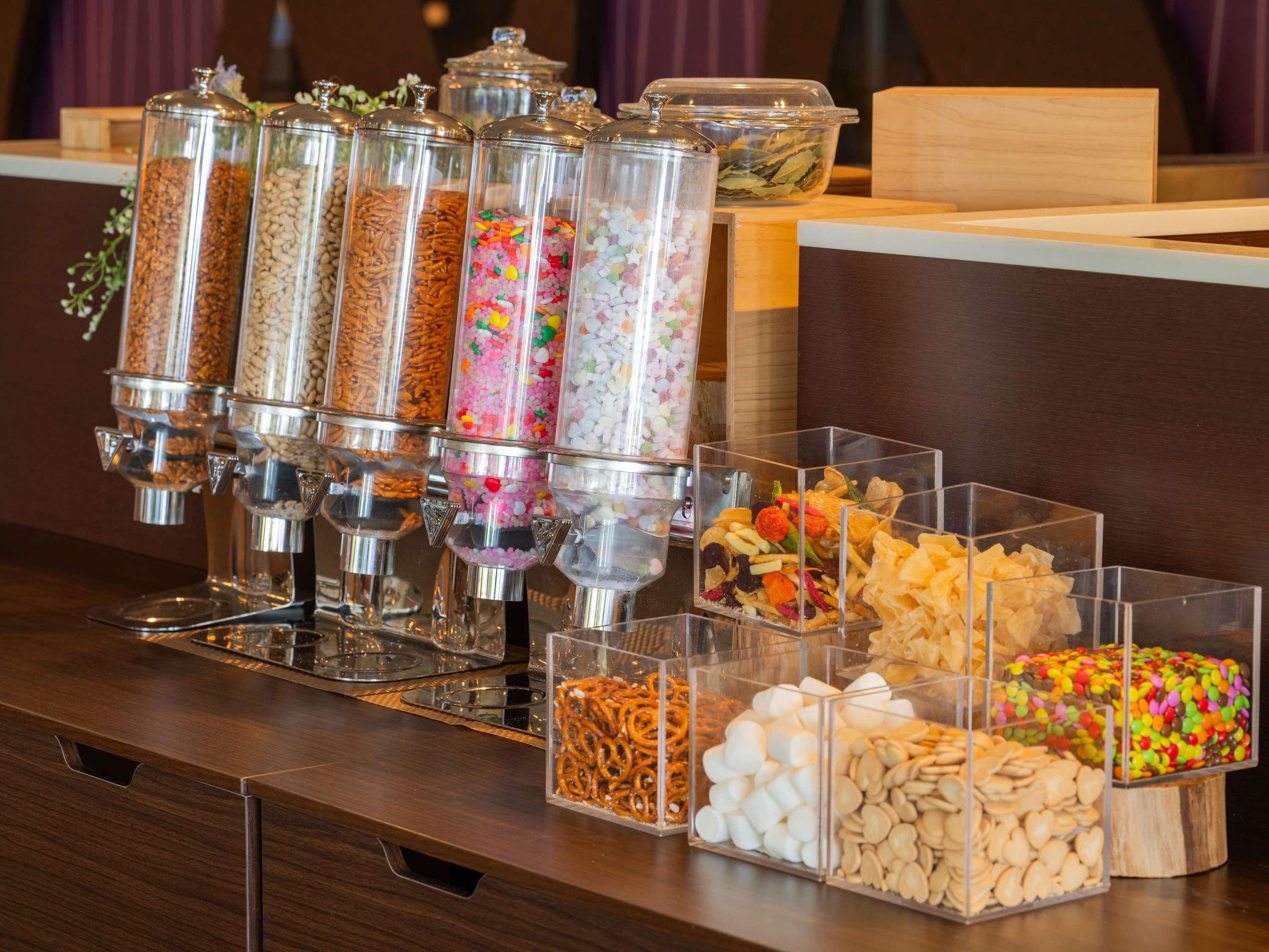 A snack bar with various containers of nuts, pretzels, marshmallows, and colorful candies.