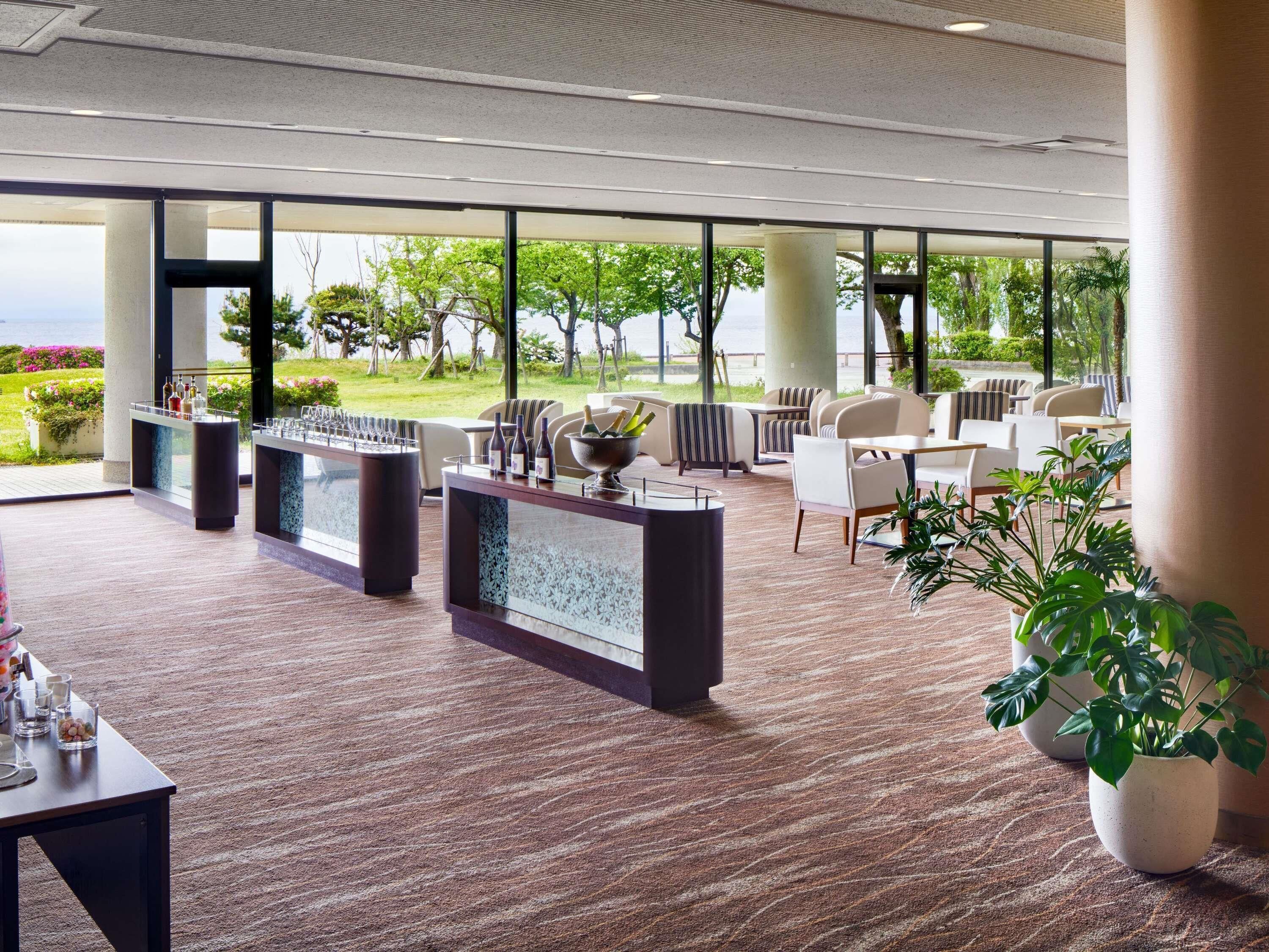 Un moderno vestíbulo de hotel con mostrador de recepción, zona de estar y grandes ventanales que ofrecen vistas al exterior.