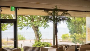 Een restaurant met terras, een palmboom en uitzicht op zee.