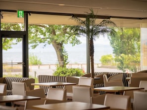 Un restaurant avec une terrasse, un palmier et une vue sur la mer.