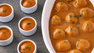 A bowl of soup with dumplings garnished with herbs.