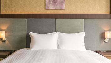 A hotel room with a large bed, two bedside lamps, a headboard with a textured panel, and a wall-mounted artwork.