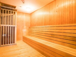 Un sauna avec des bancs en bois et une porte en métal.