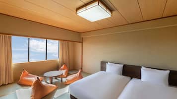 Quarto de hotel com uma cama grande, uma mesinha redonda e dois travesseiros laranja.