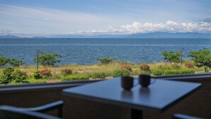 Uitzicht op zee met een tafel en stoelen, een heldere lucht en verre bergen.
