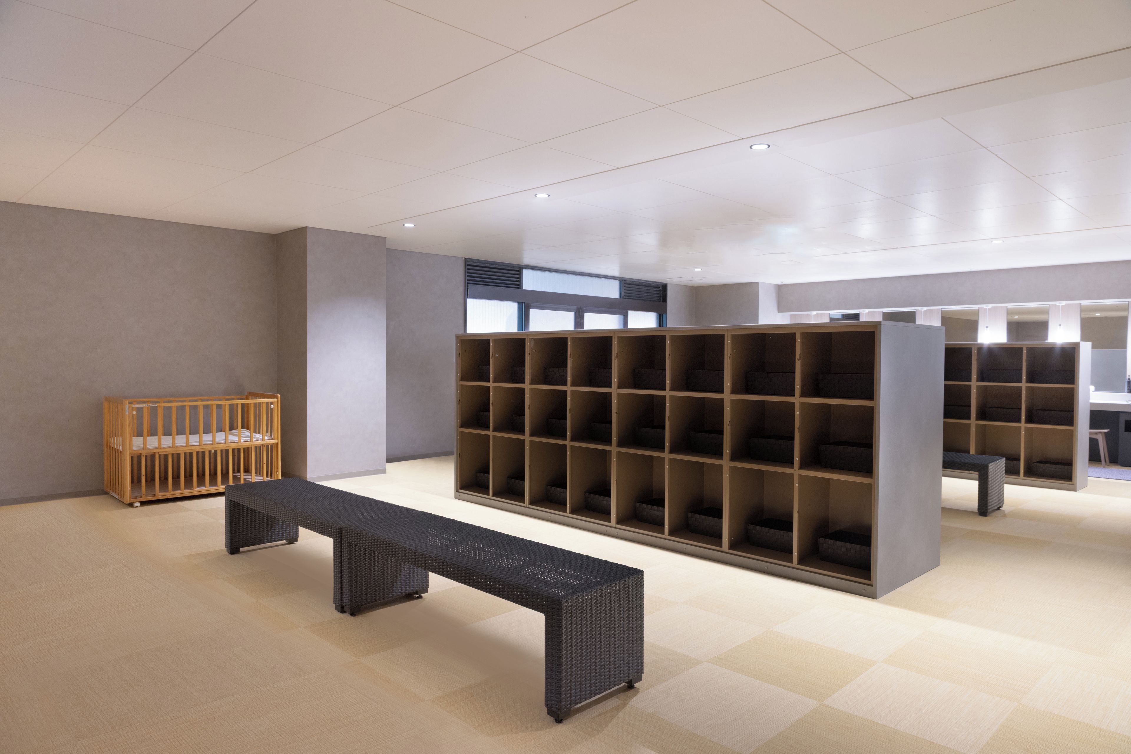 Um interior moderno com um berço de madeira, um banco e uma estante grande.