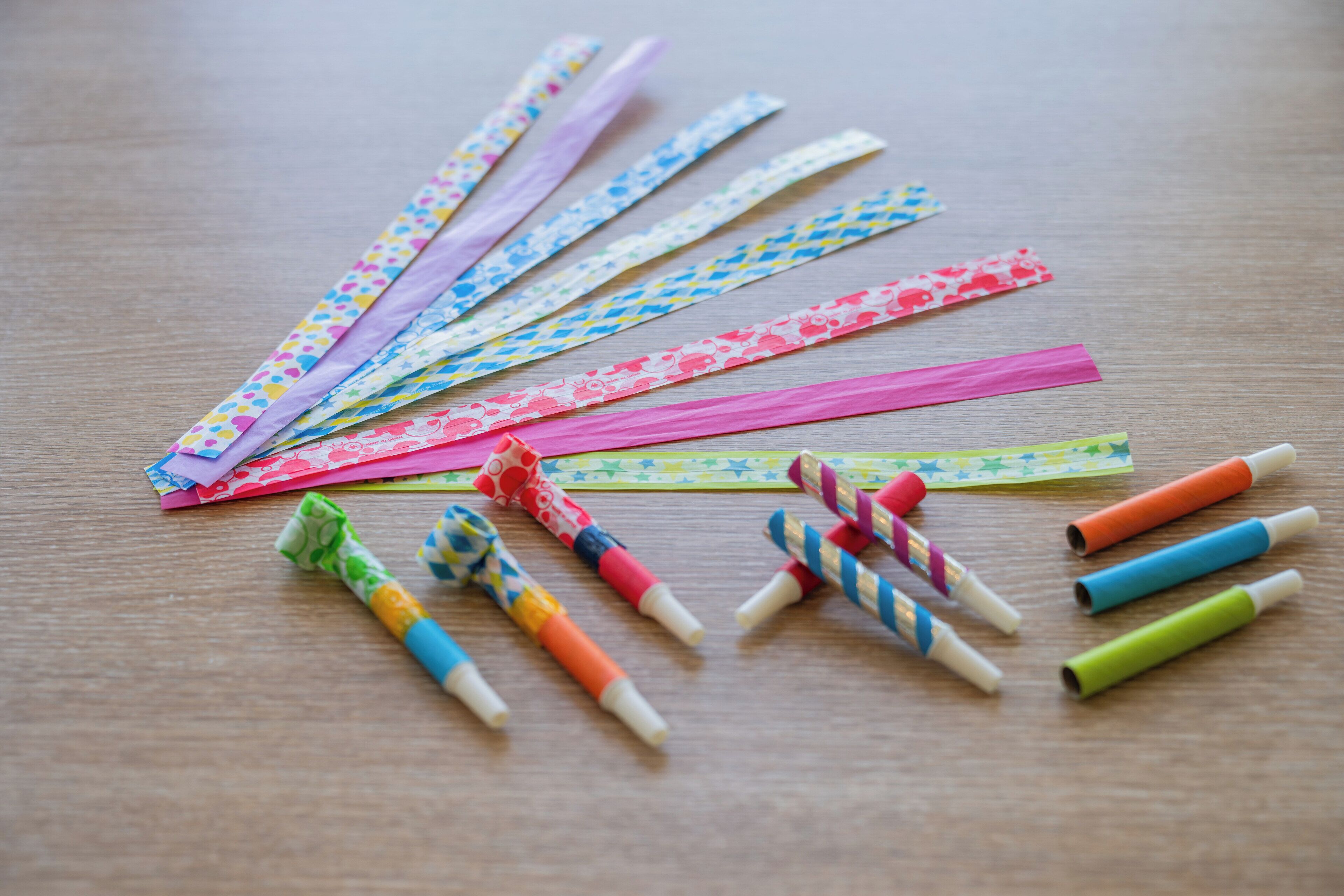 Diverse gekleurde papierstroken en stiften op een houten ondergrond.