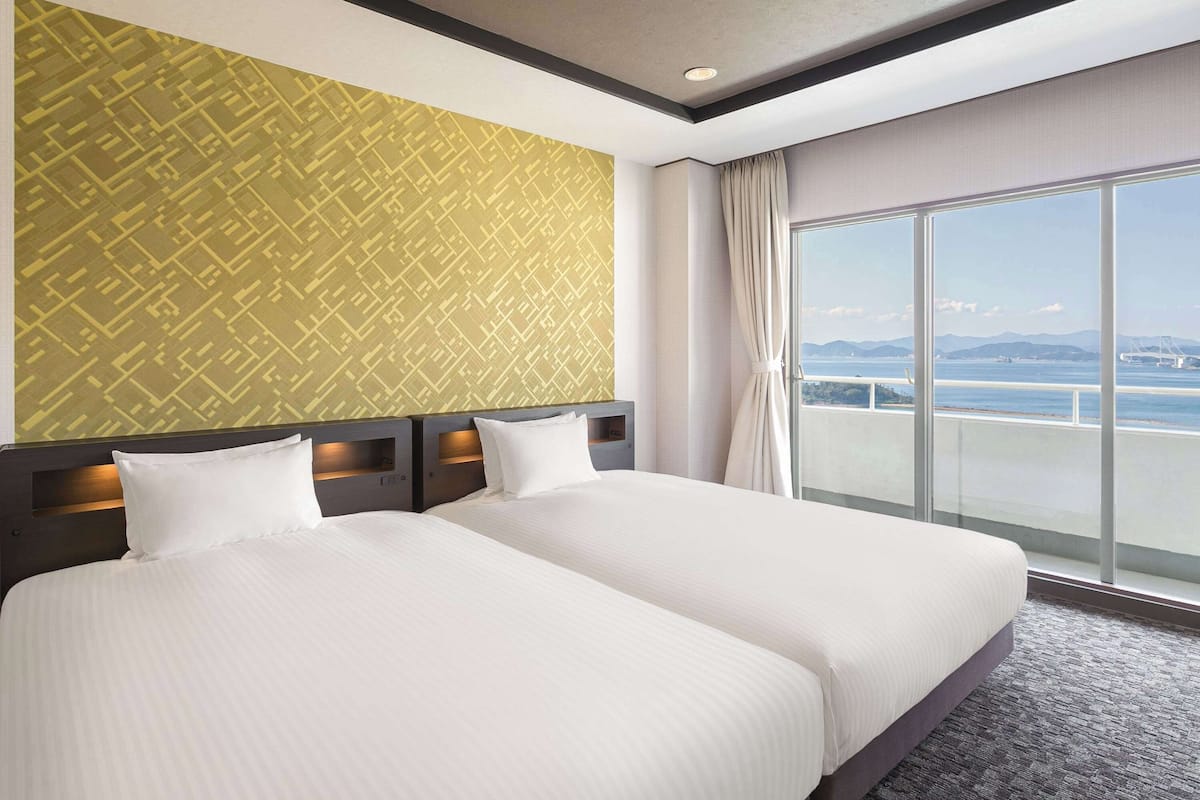 Relax in this stylish room with a large bed, headboard lighting, and a scenic view of a bridge and mountains.