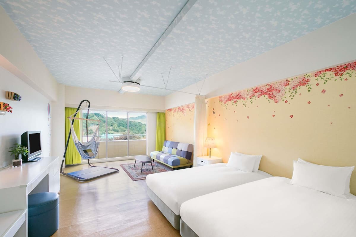 A hotel room with a bed, a sofa, a desk, a chair, and a view of the outdoors.