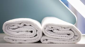 Two rolled white towels stacked on a surface.