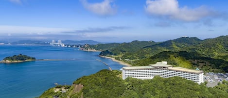 A coastal hotel with a view of the sea and mountains.