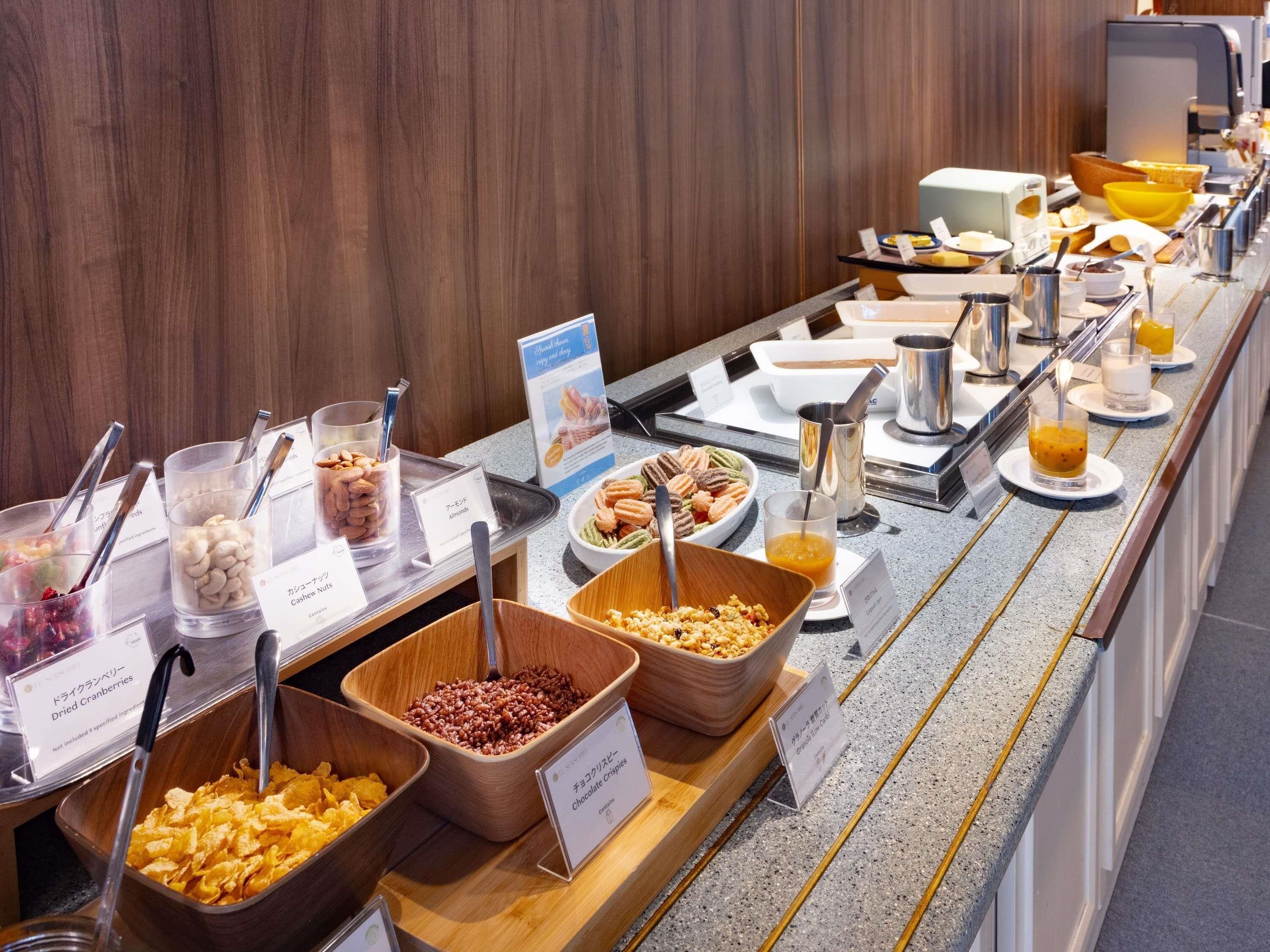 Un buffet proposant une variété d’aliments, notamment des noix, des canneberges séchées, des biscuits au chocolat et un assortiment de boissons.