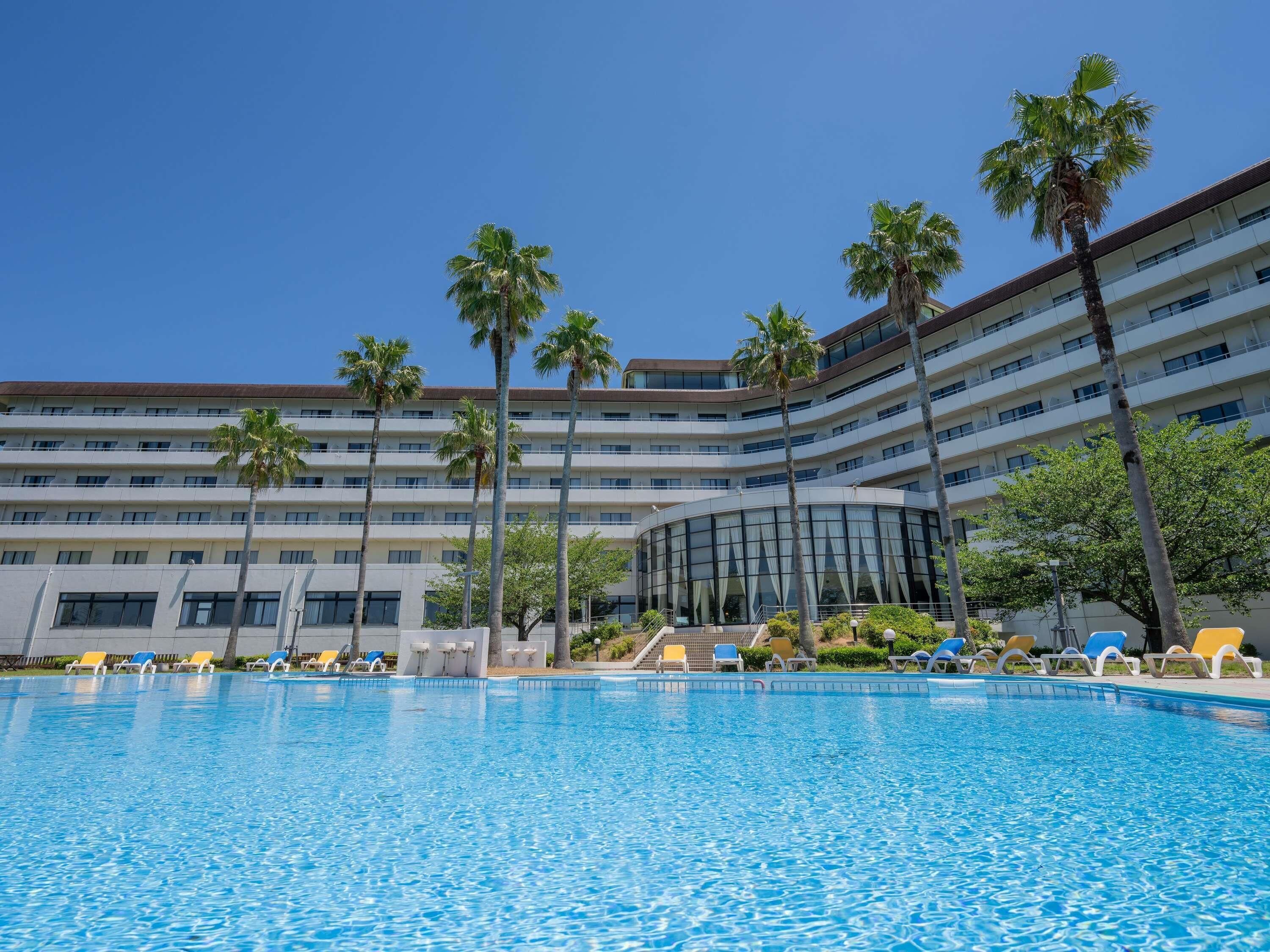 Un hôtel doté d’une piscine, de palmiers et d’un immeuble à plusieurs étages.
