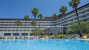 Un hotel con piscina, palmeras y un edificio de varios pisos.