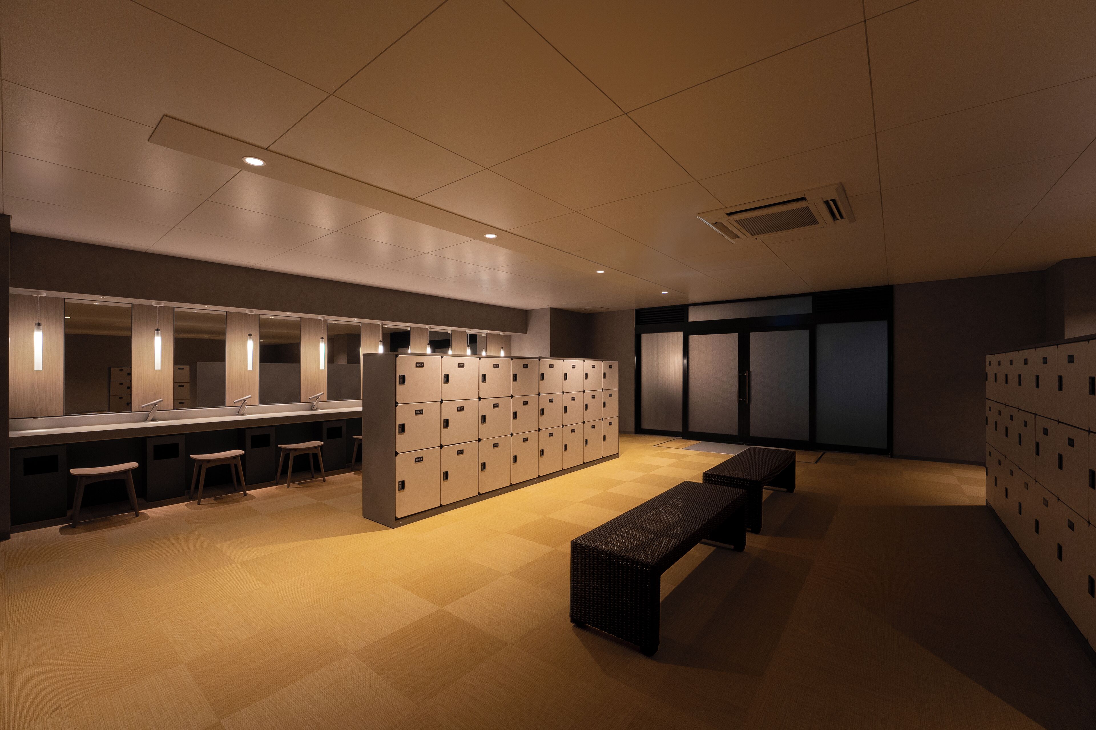 A restroom with multiple sinks, benches, and lockers.