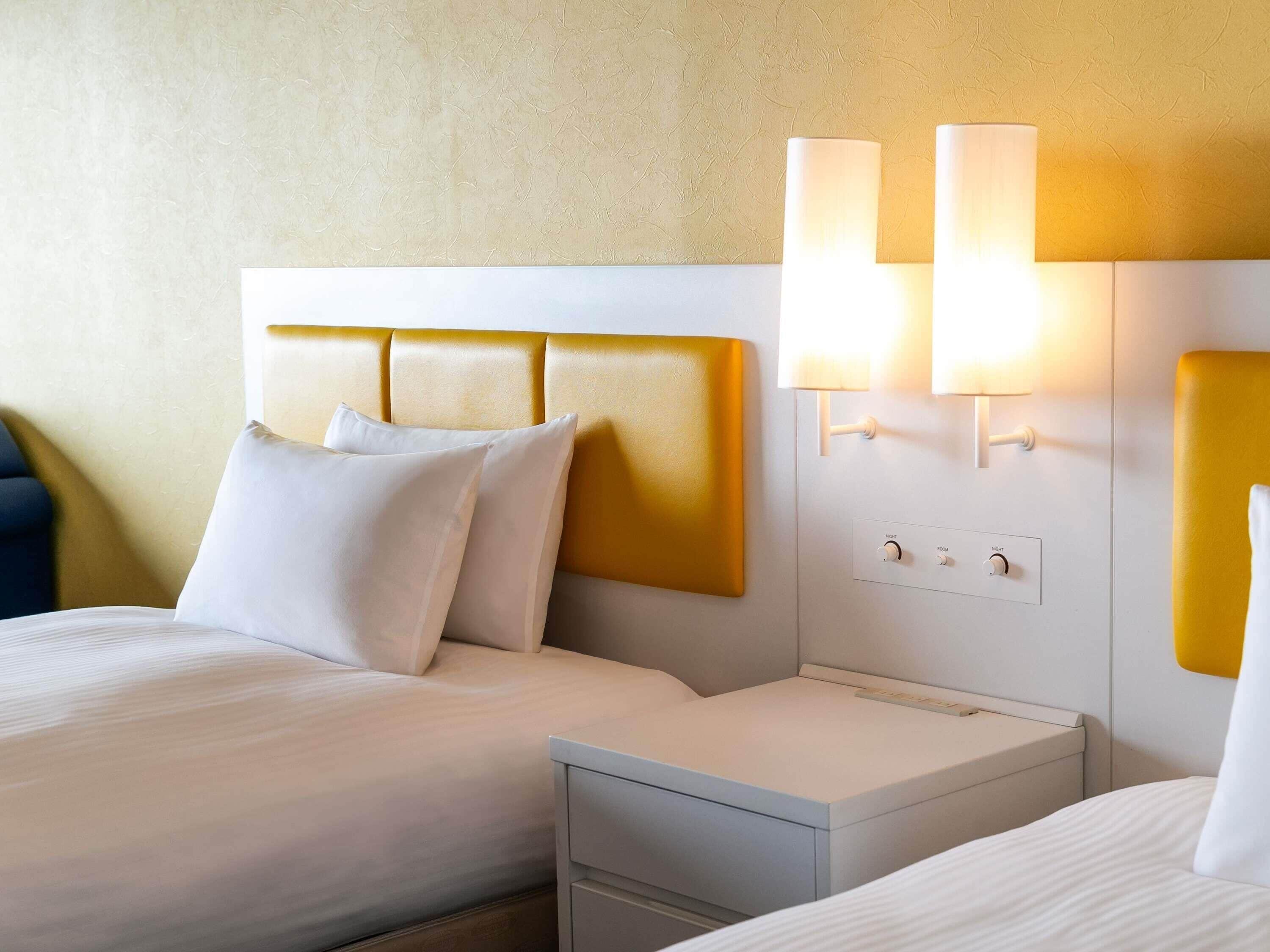 Quarto de hotel com cama, mesas de cabeceira e luminárias fixadas na parede.