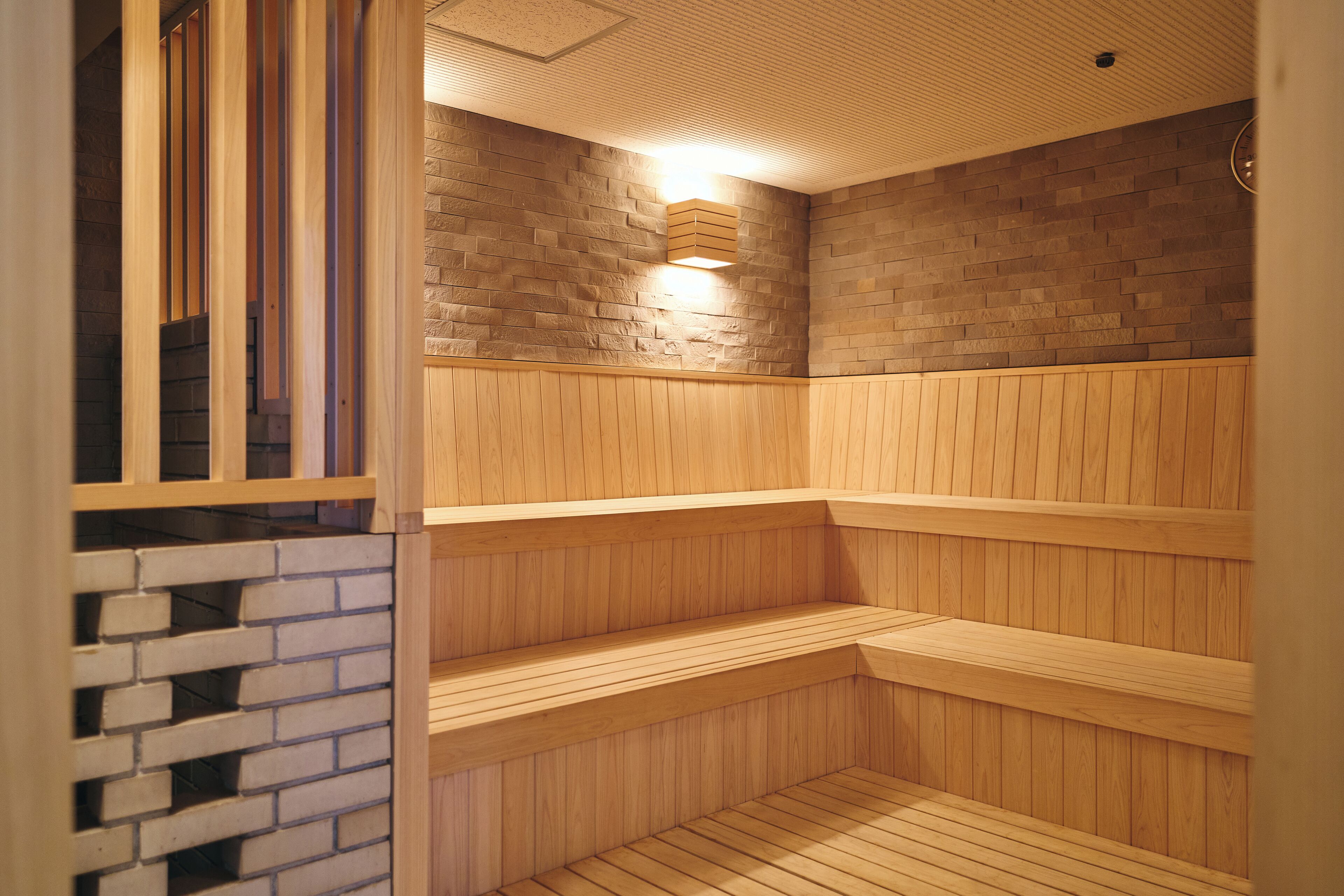A sauna with wooden benches and a brick wall.