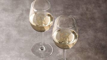 Two clear glasses of white wine on a textured surface.