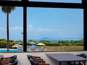 Una habitación con un ventanal que da a una zona de piscina con sombrillas y sillones de descanso.