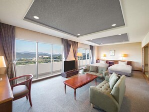 Una habitación de hotel con una cama grande, un sofá, un televisor y un balcón con vistas a las montañas.