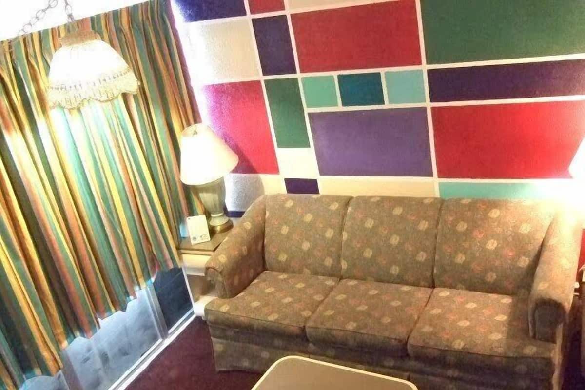 A living room with a sofa, a small table, and a colorful wall.