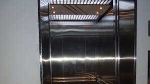 Ein glänzendes Aufzuginnere mit reflektierenden Oberflächen und mehreren Leuchten an der Decke.