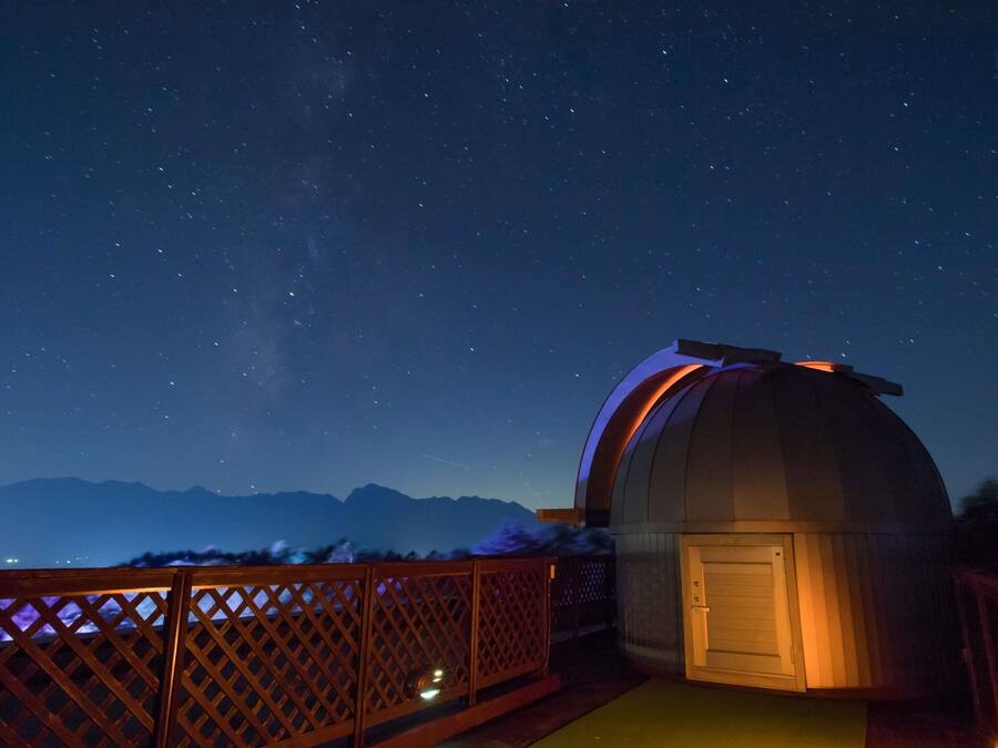 A dome-shaped observatory with a wooden deck and a view of the night sky.
