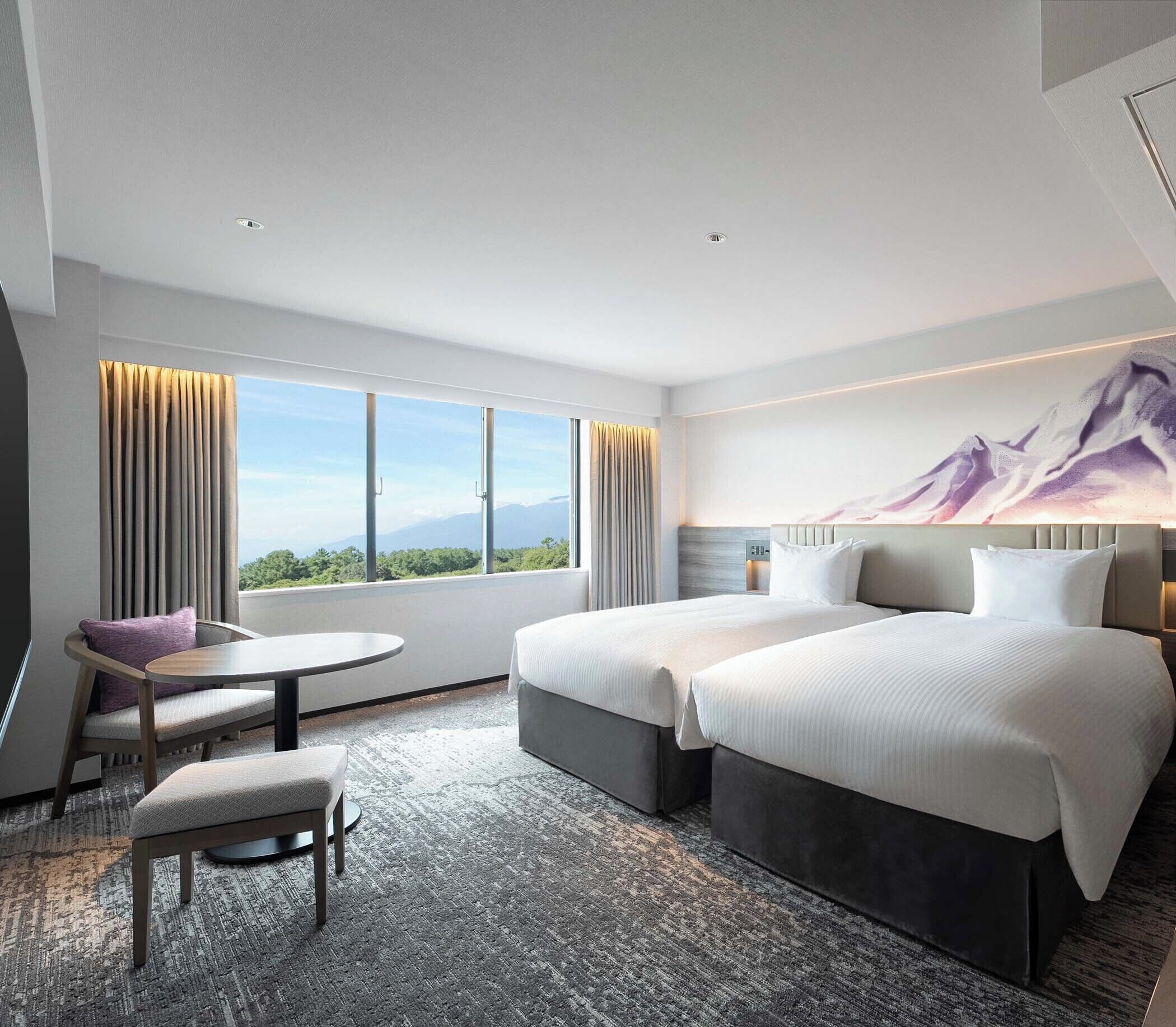 A modern hotel room with two beds, a desk, and a chair.