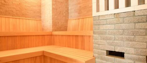 A sauna with wooden benches and a stone wall.