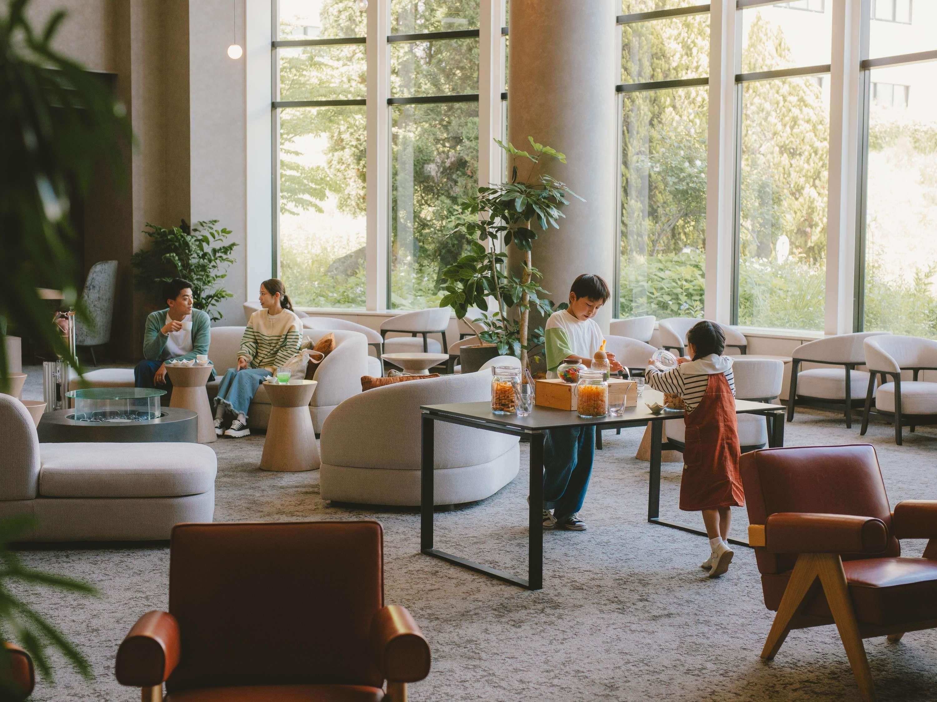 A spacious indoor area with large windows, comfortable seating, and a central table with jars.