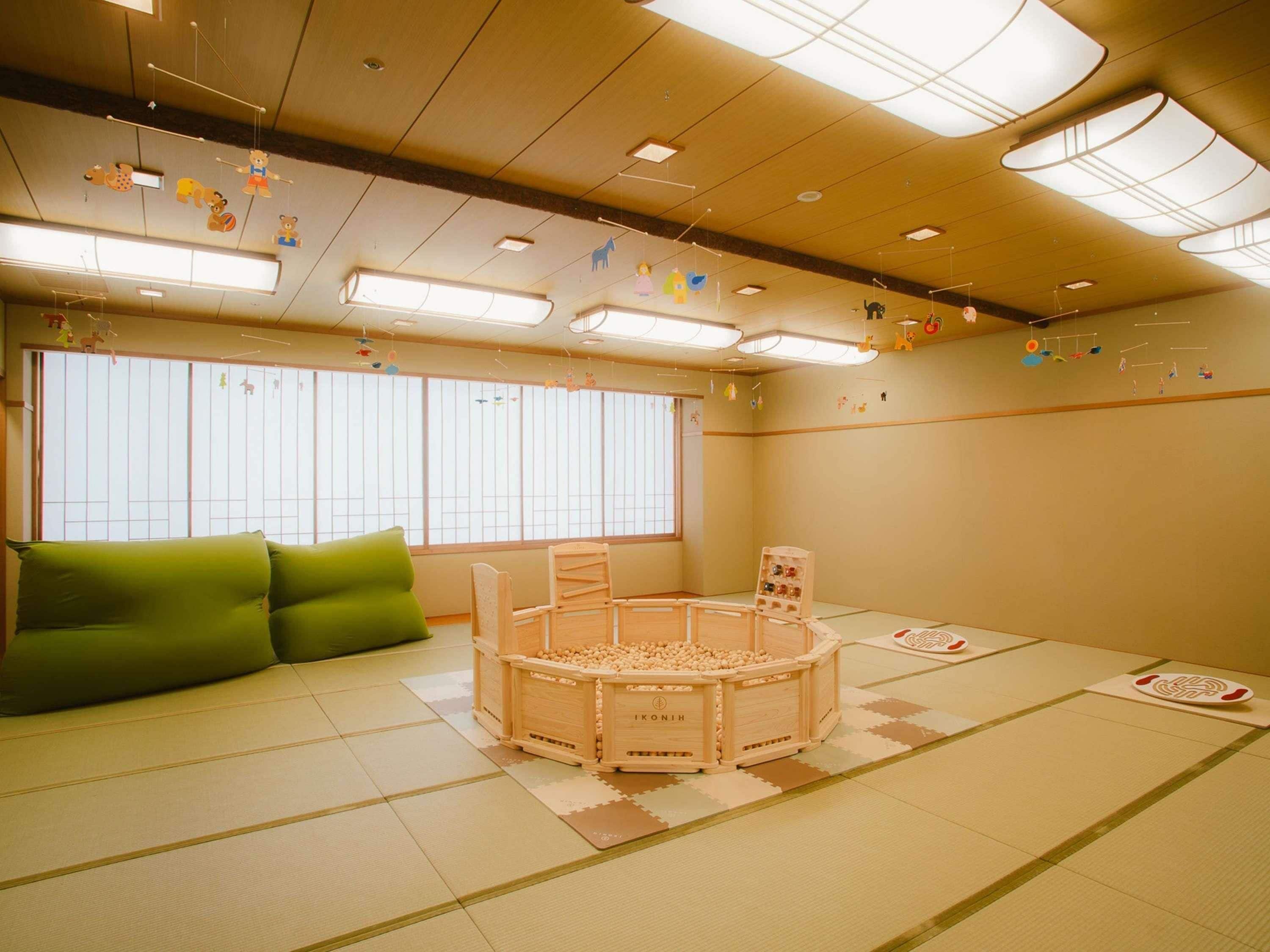 A tatami mat room with a tatami mat sofa, a wooden playpen, and a shoji screen window.