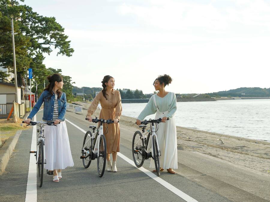 Trois personnes sur une piste cyclable aménagée, le long d’une étendue d’eau, chacune à vélo.