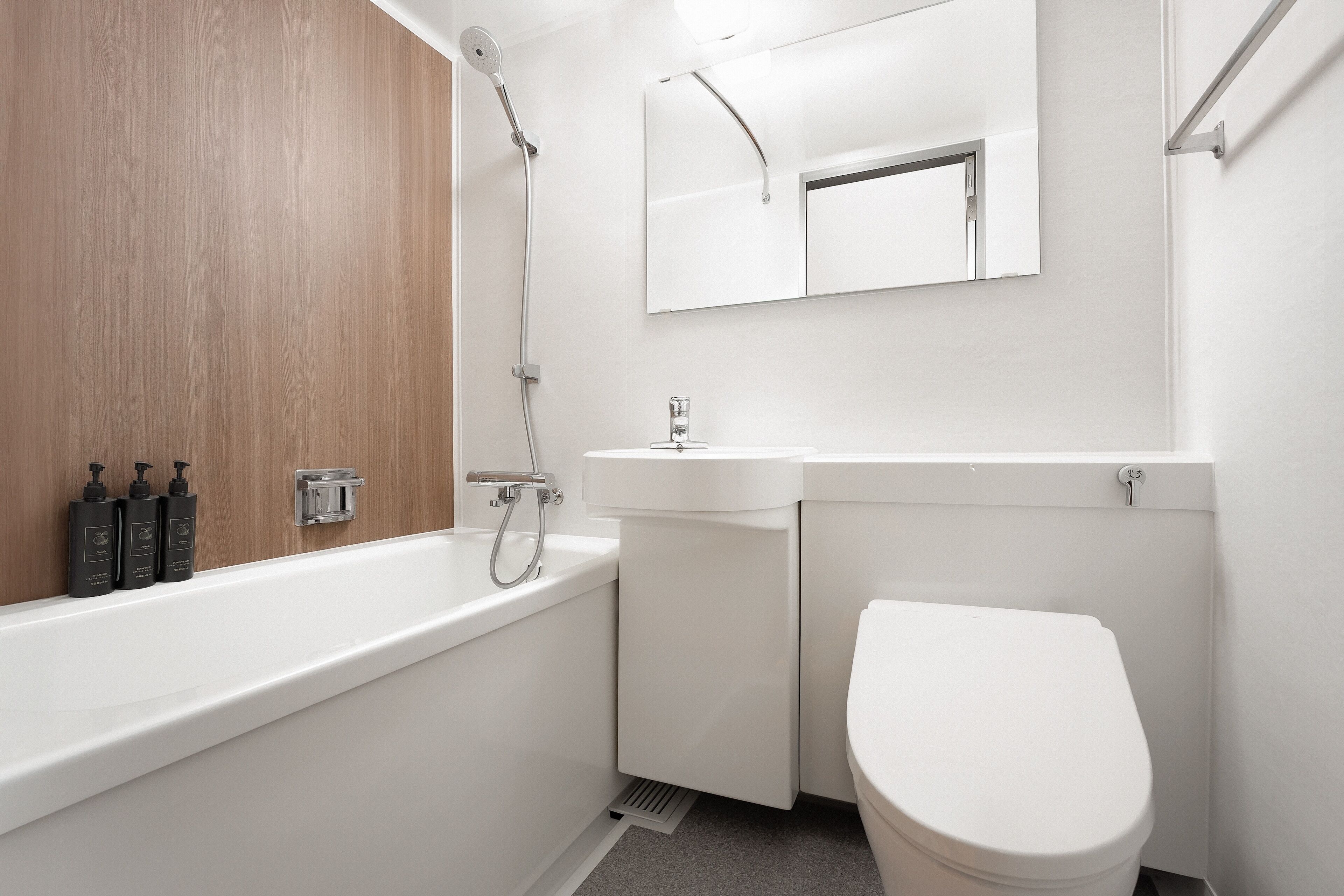 Ein modernes Badezimmer mit einem Holz-Waschtisch, einer weißen Badewanne und einer Toilette.